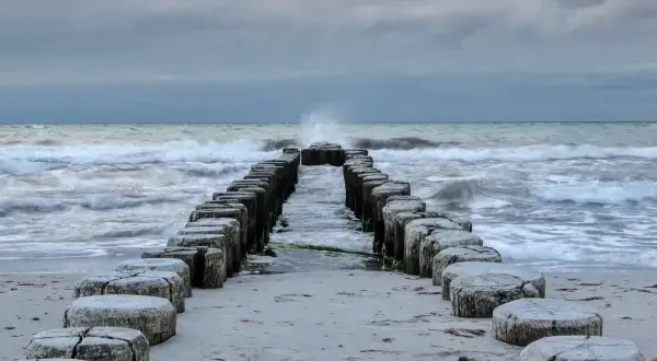 Kamienne pale wchodzące w morze bałtyckie, które jest częścią oceanu. Fale rozbijają się o brzeg.
