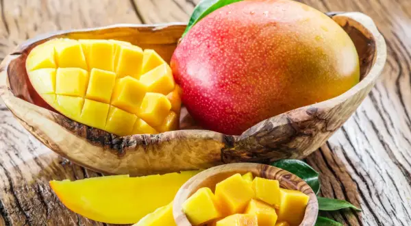 Soczysty mango owoc, pokrojony w kostkę i w całości, prezentuje swoje bogactwo witamin.