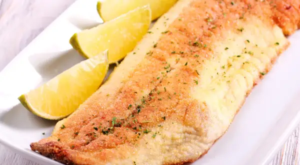 Smażony filet z ryby amur, podany z ćwiartkami limonki. Delikatny smak amura świetnie komponuje się z cytrusową nutą.