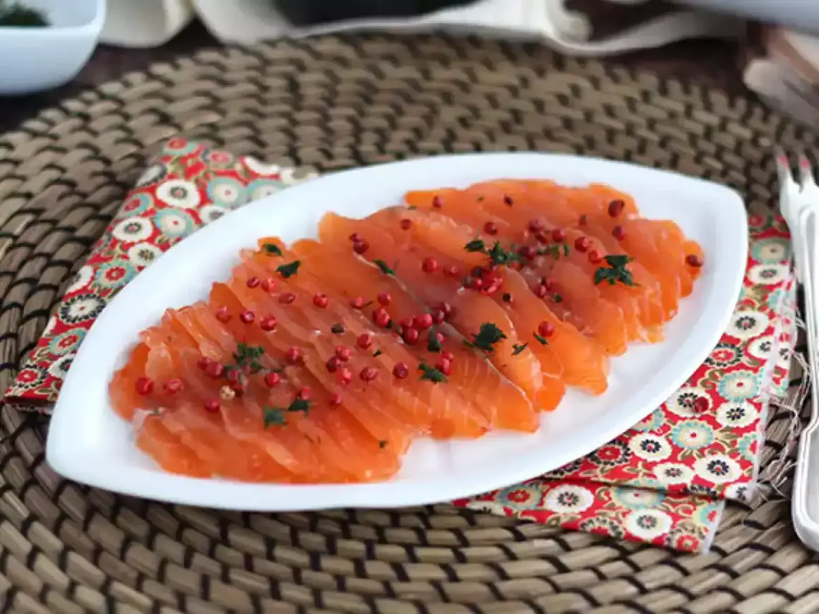 Pięknie pokrojony łosoś, idealny do gravlax przepis. Posypany różowym pieprzem i ziołami, prezentuje się apetycznie.