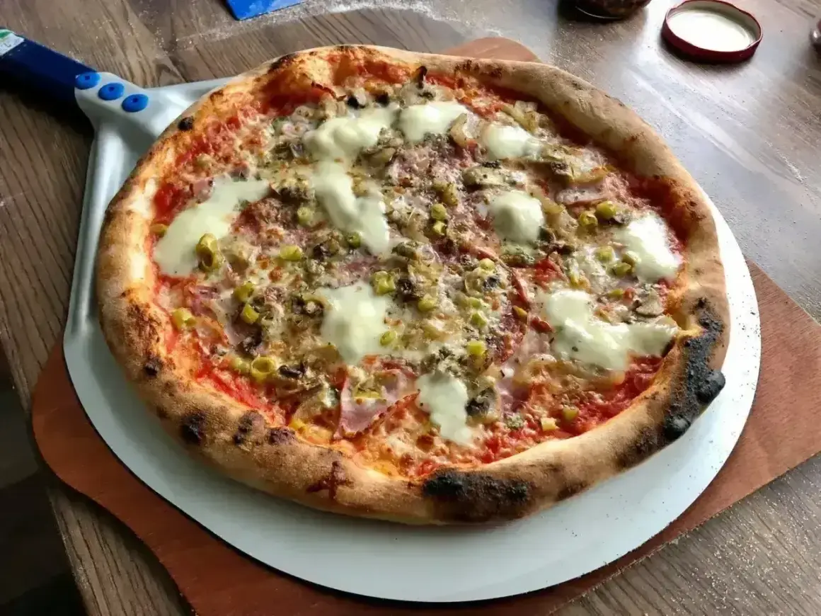 Pyszna pizza z grilla, z chrupiącym brzegiem, roztopionym serem i kolorowymi dodatkami, gotowa do podania.