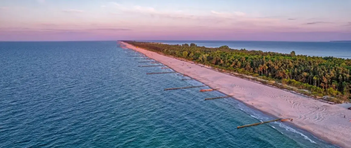 Zachód słońca nad Bałtykiem, gdzie widać piaszczystą plażę i las, tworzące najwęższe miejsce na Helu.