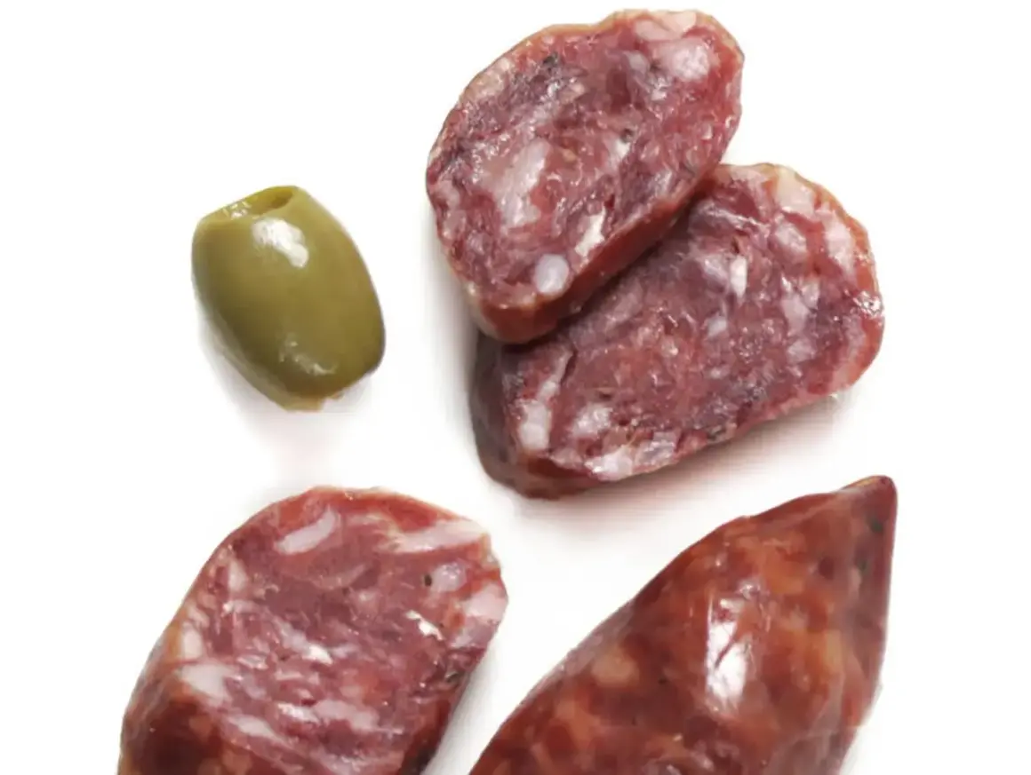 Kawałki salsiccia, czyli włoskiej kiełbasy, i zielona oliwka.