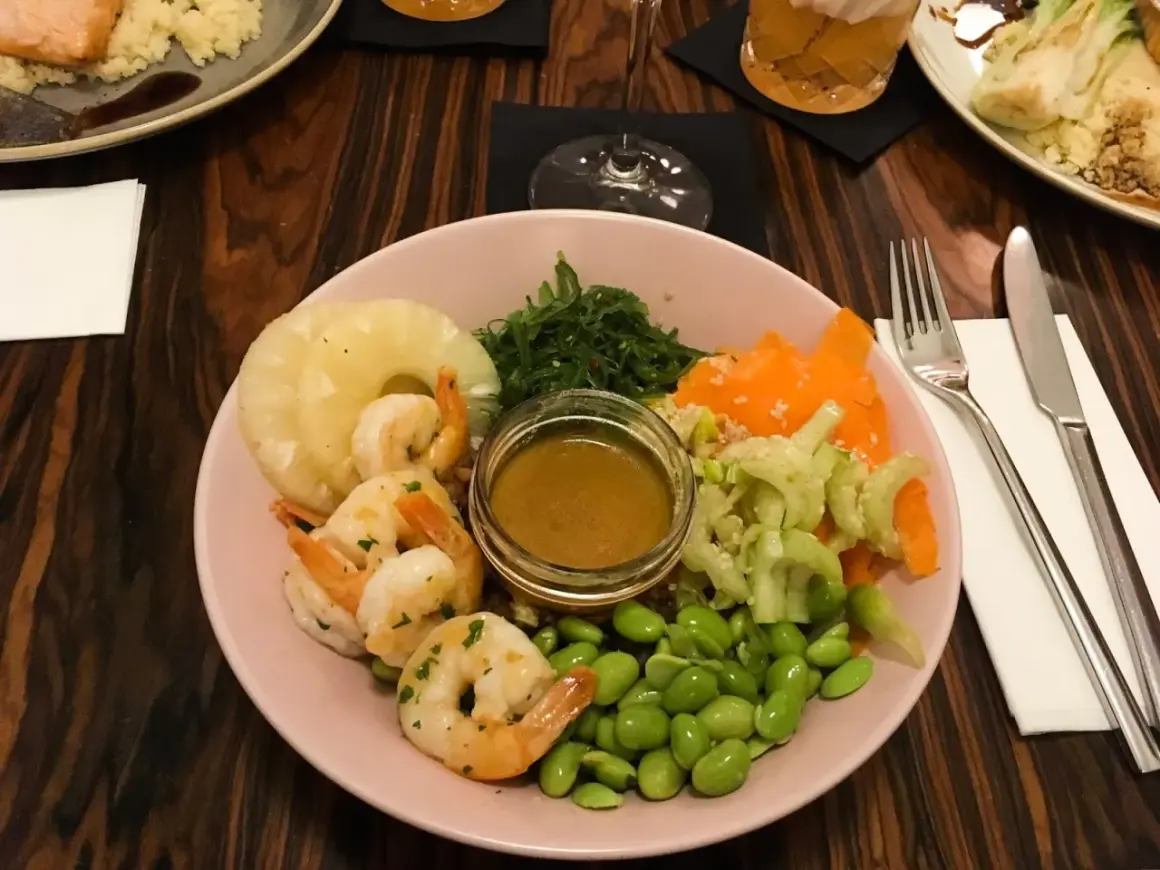 Kraków co zjeść? Kolorowa miska z krewetkami, ananasem, edamame i sosem. Idealna na lekki posiłek.