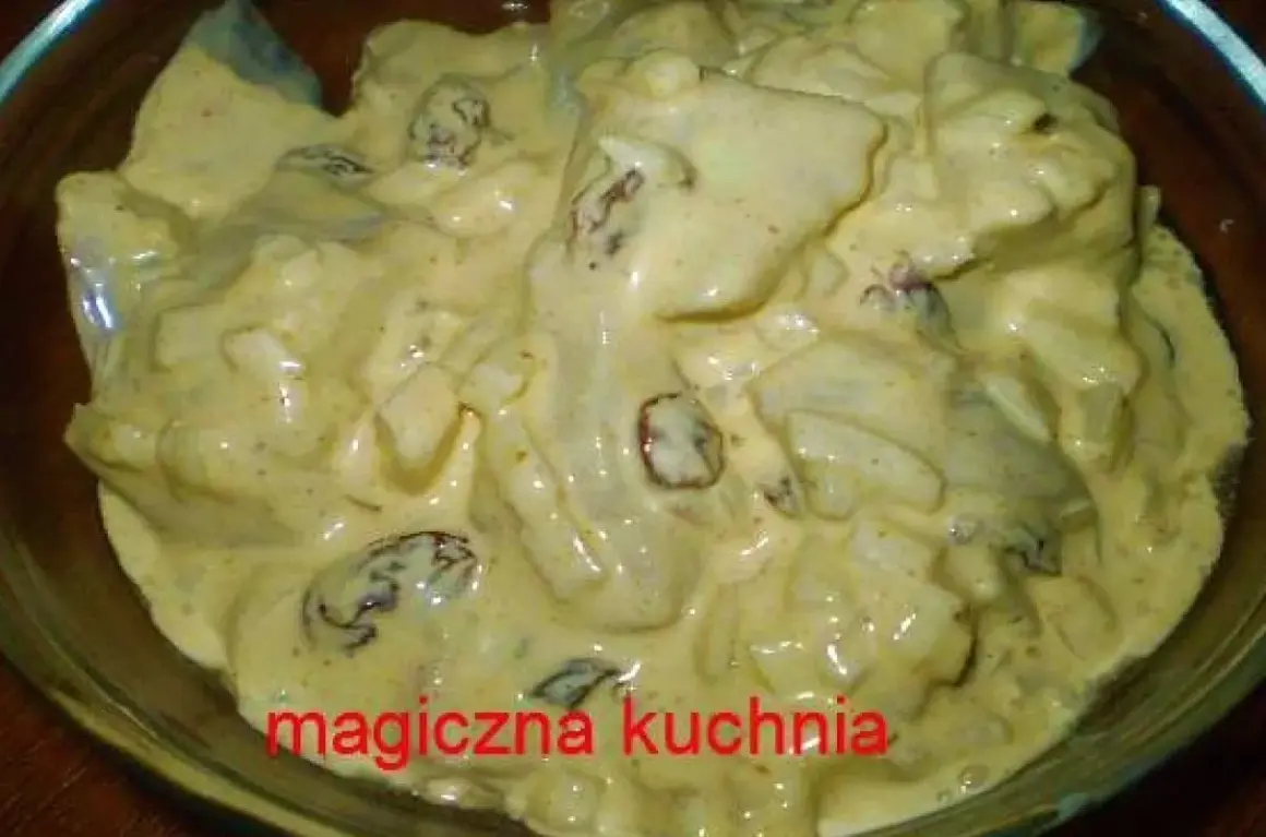 Kremowe śledzie w sosie curry z majonezem i rodzynkami, gotowe do podania.