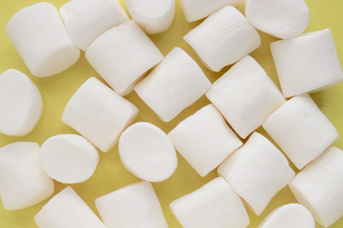 Białe, puszyste pianki marshmallow ułożone na żółtym tle. Pańska skórka, co to za słodka przyjemność!