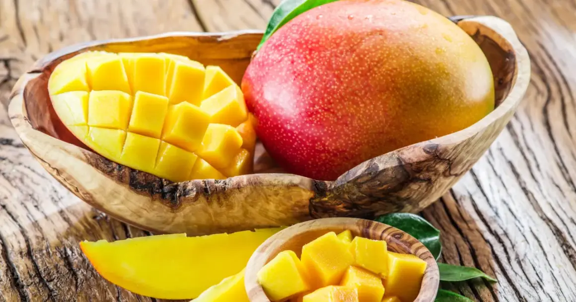Soczysty mango owoc, pokrojony w kostkę i w całości, prezentuje swoje bogactwo witamin.