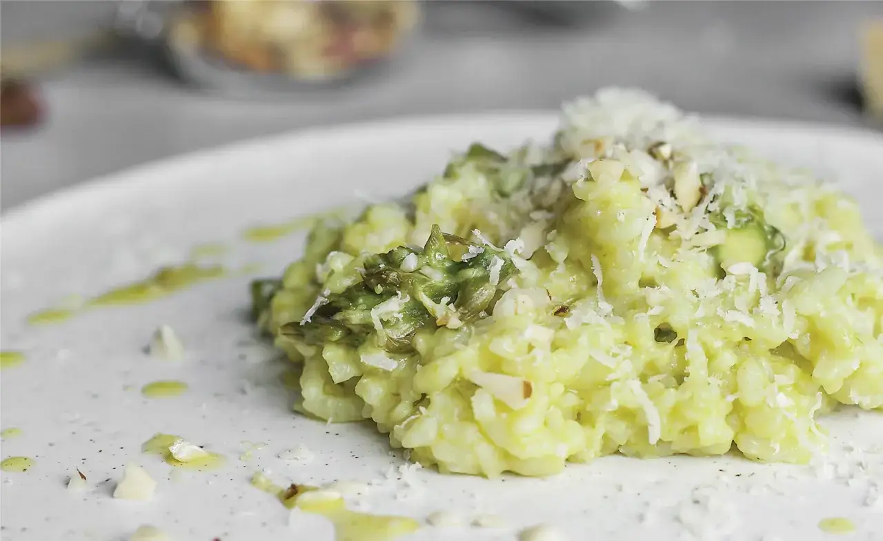 Kremowe risotto z szparagami, posypane parmezanem i migdałami. Idealny przepis podstawowy na wiosenny obiad.