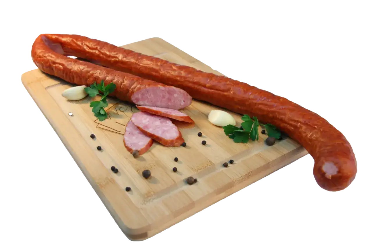Kiełbasa podwawelska, pokrojona w plastry, leży na desce z czosnkiem, pieprzem i natką pietruszki.