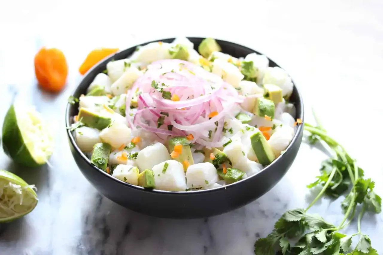 Pyszne ceviche: kawałki białej ryby, awokado, czerwona cebula i kolendra w misce. To jest właśnie ceviche co to jest!
