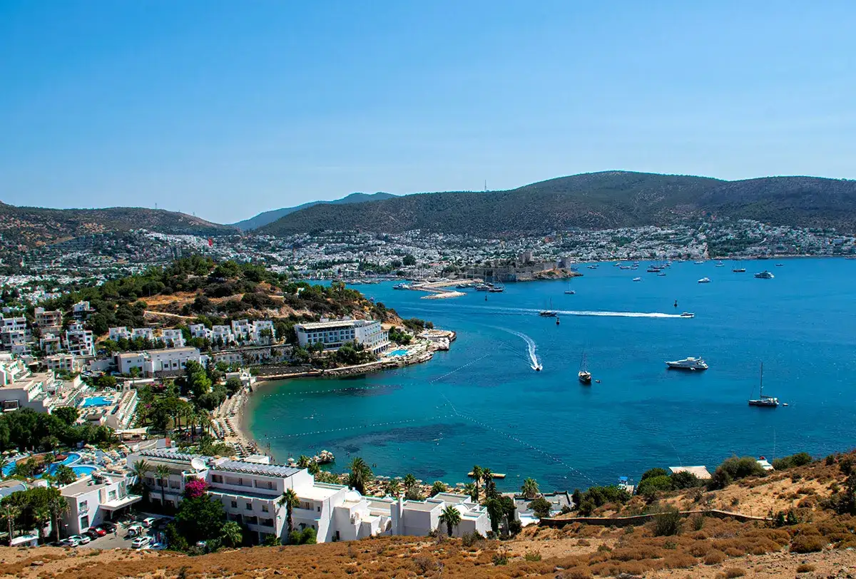 Widok na zatokę w Bodrum, gdzie turkusowe morze otacza białe budynki i zamek.