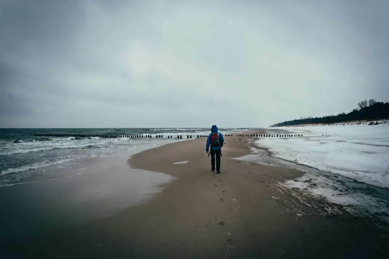 Spacer po plaży na Helu poza sezonem. W oddali widać las i zimowy krajobraz.