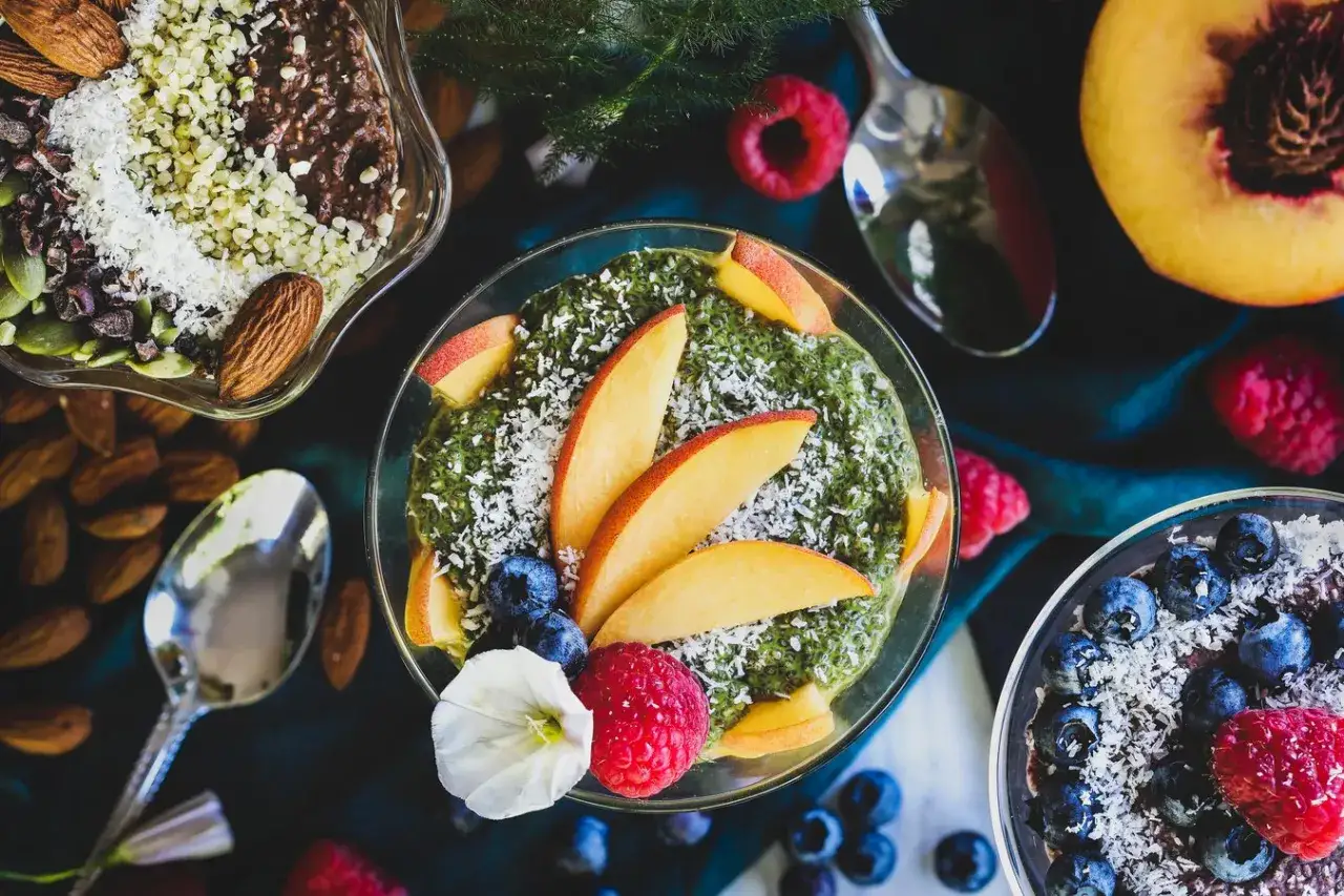 Pyszne nasiona chia przepisy: zielony smoothie bowl z brzoskwiniami i jagodami, czekoladowy deser z migdałami i owocami.