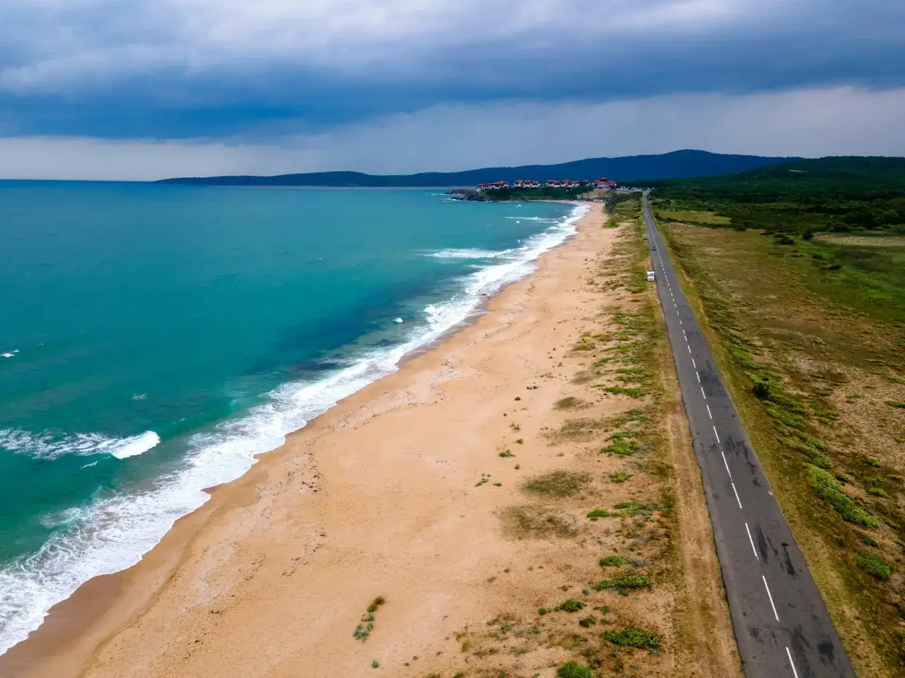 Piękna plaża i turkusowe morze w Bułgarii. Droga wzdłuż wybrzeża prowadzi do urokliwych domków.