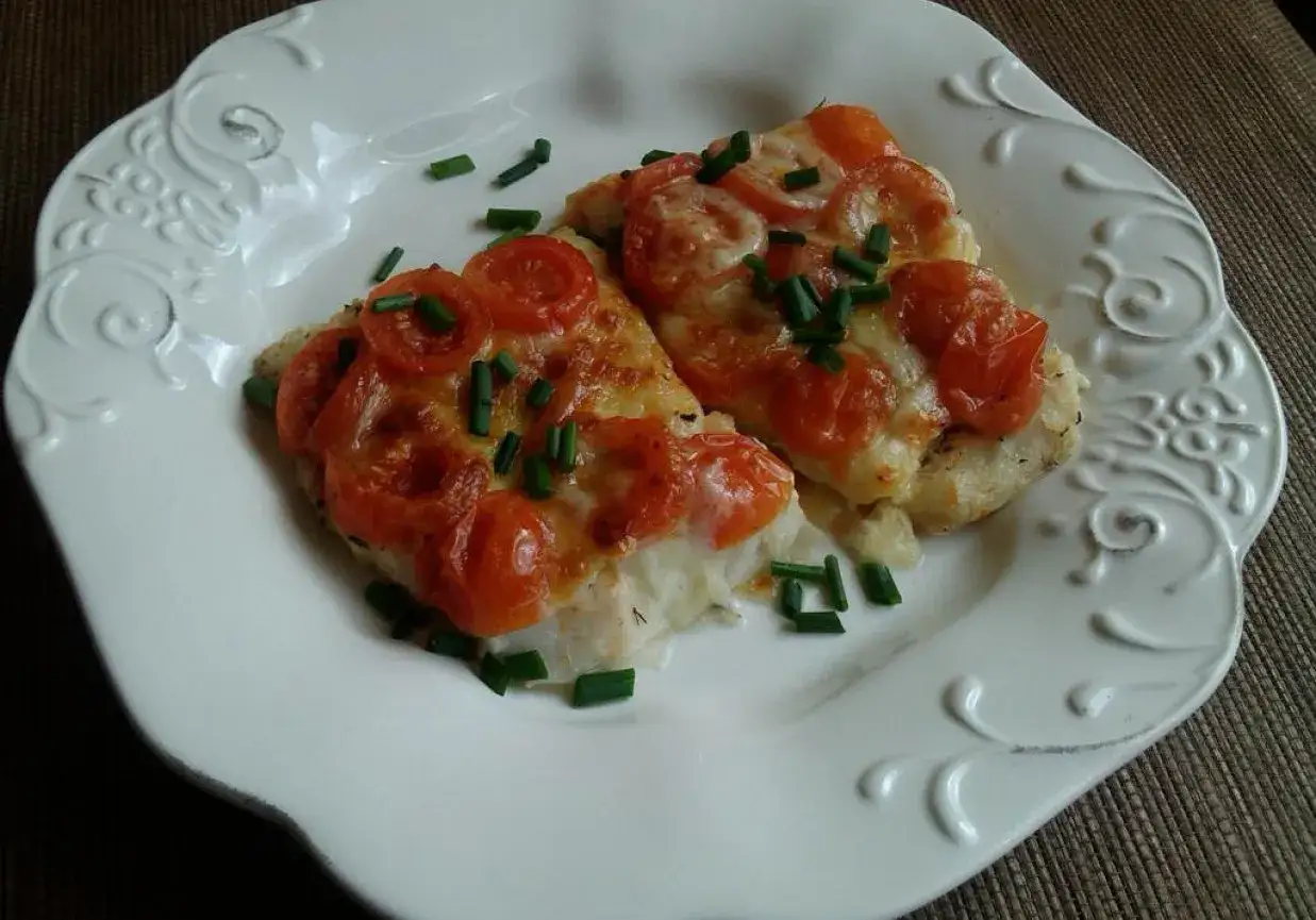Ryba amur jak smakuje? Delikatna, pieczona z pomidorami i serem, posypana szczypiorkiem. Pyszne danie!
