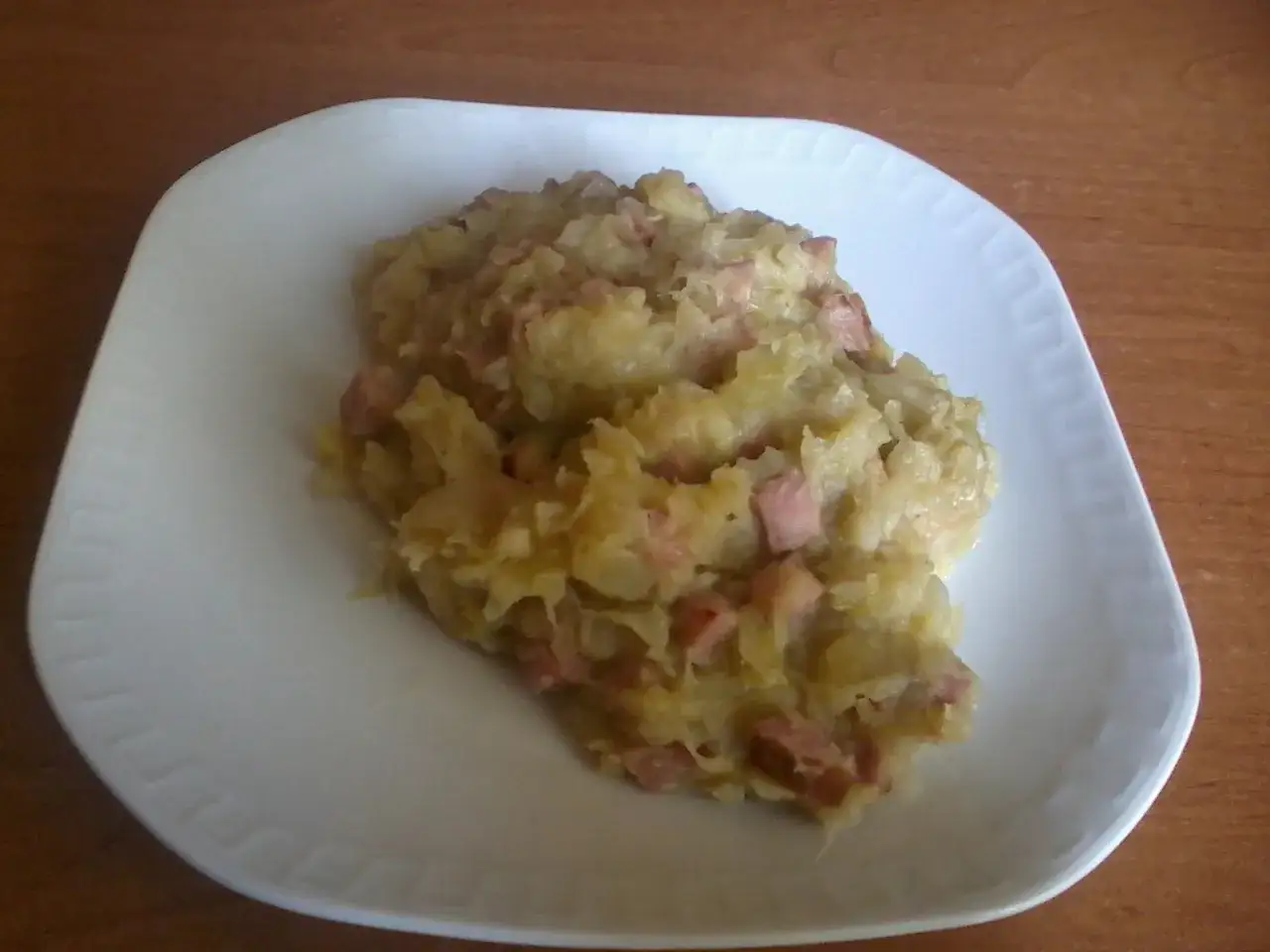 Pazibroda, czyli ziemniaki z boczkiem i cebulką, na białym talerzu.