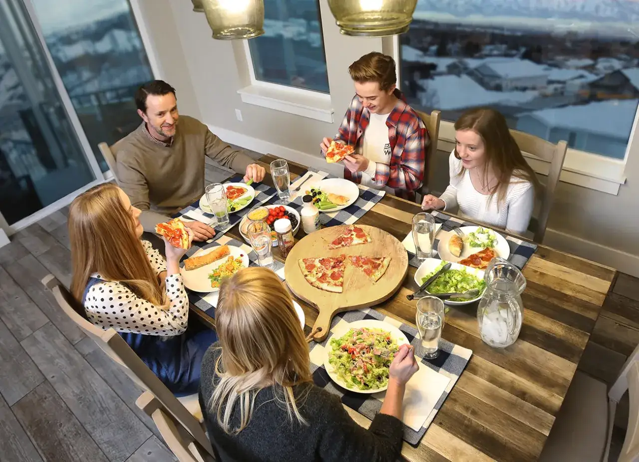 Rodzina cieszy się pyszną pizzą i sałatką. Szybki obiad dla dzieci i dorosłych, który łączy wszystkich przy stole.