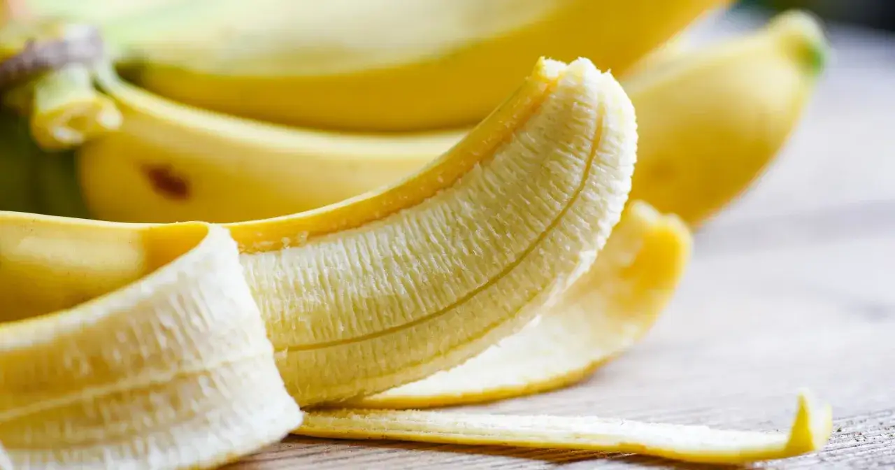 Banan częściowo obrany, ukazujący jego biały miąższ. Zastanawiasz się, ile potasu ma banan? Ten owoc jest jego bogatym źródłem.