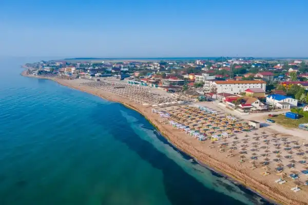 Widok na plażę z rzędami leżaków i parasoli. W tle zabudowania kurortowe. Woda w morzu czarnym jest ciepła, idealna do kąpieli.