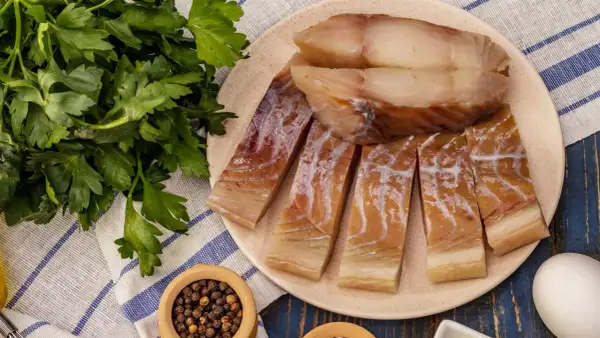 Pokrojona w plastry ryba czerniak, gotowa do podania z natką pietruszki i pieprzem.