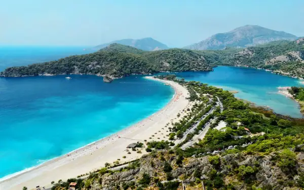 Widok na zatokę z turkusowym morzem, plażą i górami w tle. Bodrum zachwyca swoim morzem.