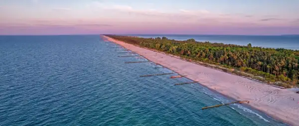 Zachód słońca nad Bałtykiem, gdzie widać piaszczystą plażę i las, tworzące najwęższe miejsce na Helu.