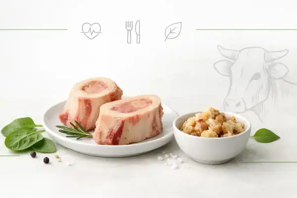 Dwa kawałki wołowego szpiku na talerzu, obok miseczka z chrupiącymi skwarkami. Odkryj niezwykłe szpik wołowy właściwości.