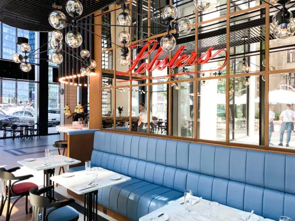 Elegancka restauracja z niebieskimi kanapami i neonem "Lobsters". Idealne miejsce na romantyczną kolację, które z pewnością znajdzie się w rankingu restauracji Warszawa.