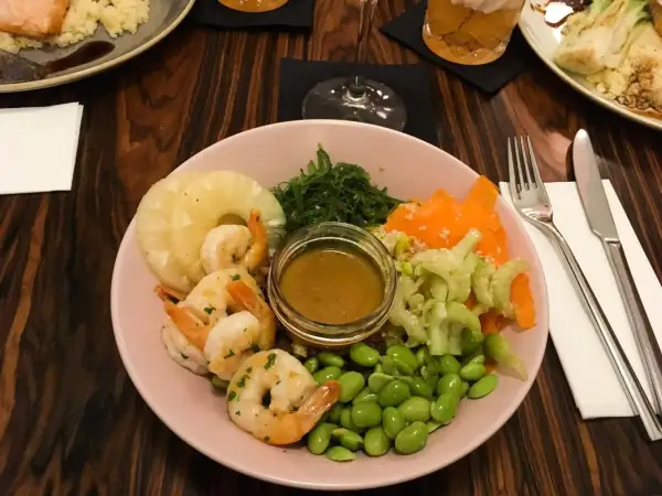 Kraków co zjeść? Kolorowa miska z krewetkami, ananasem, edamame i sosem. Idealna na lekki posiłek.