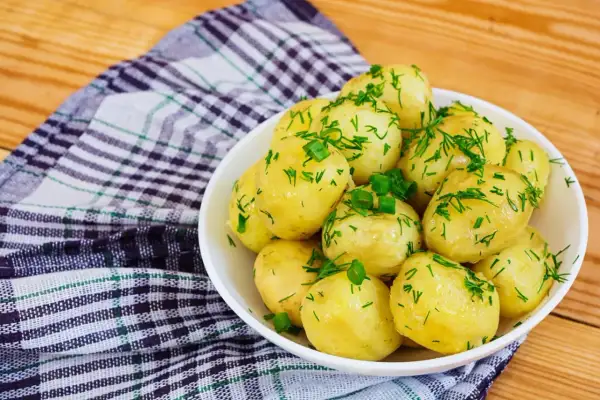 Pyszne, młode ziemniaki posypane koperkiem i szczypiorkiem. Idealne, gdy zastanawiasz się, ile się gotuje ziemniaki.