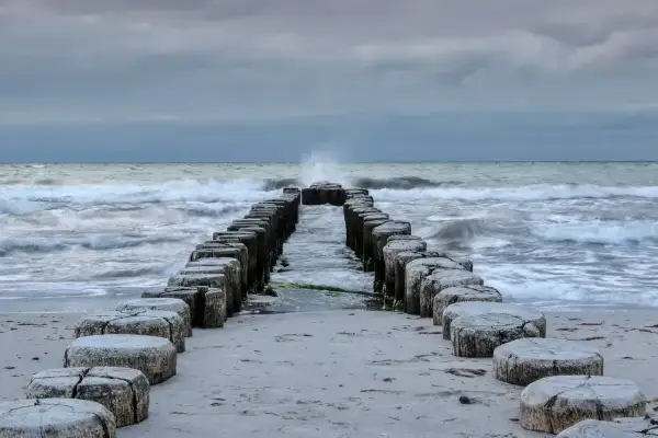 Kamienne pale wchodzące w morze bałtyckie, które jest częścią oceanu. Fale rozbijają się o brzeg.